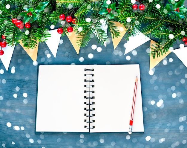 Top view of Christmas background with blank open notepad pencil christmas decorations and bokeh