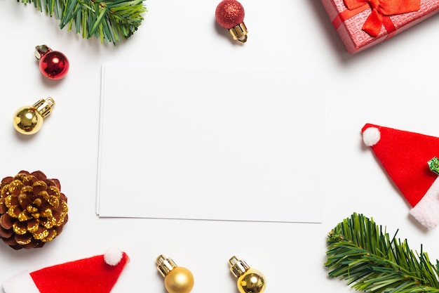 Composizione di natale vista dall'alto. regali, pigne e decorazioni rosse dei cappelli di babbo natale di natale su fondo bianco. felice anno nuovo concetto.