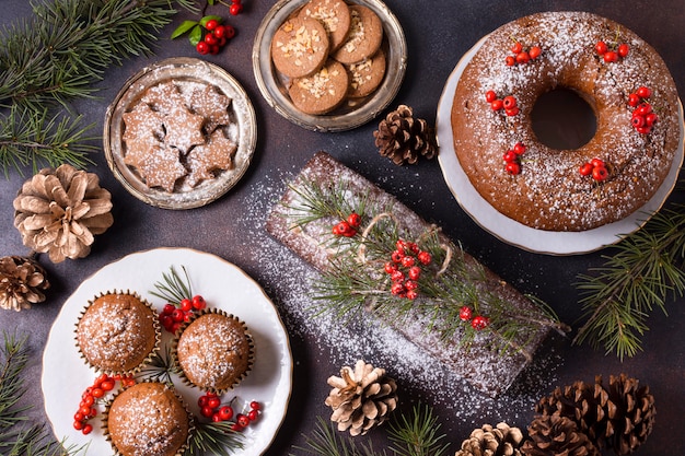 Top view of christmas desserts with red berries and pine cones