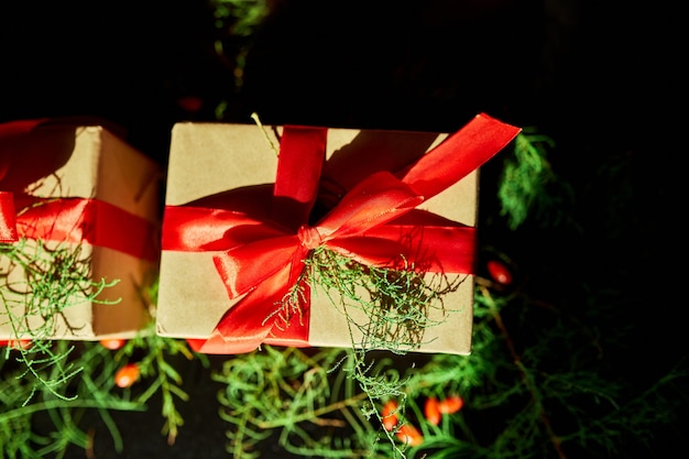 Foto vista dall'alto natale imballaggio ecologico carta kraft e rami di abete regali per le festività natalizie su sfondo nero