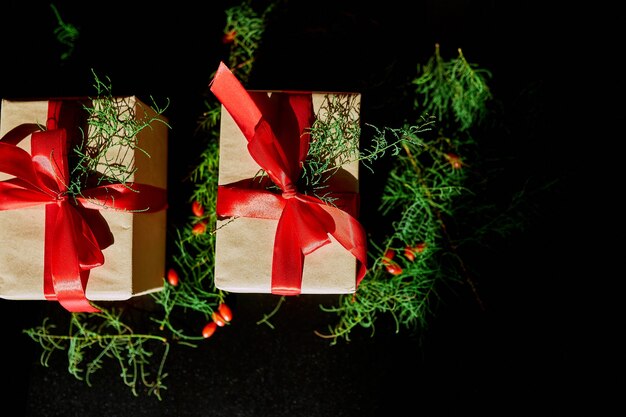 Foto vista dall'alto natale imballaggio ecologico carta kraft e rami di abete regali per le festività natalizie su sfondo nero