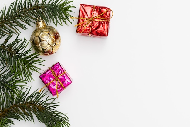 Top view of Christmas gift box red balls with spruce branches pine cones red berries and bell on white background