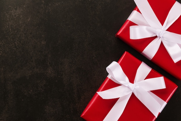 Top view of Christmas gift boxes wrapped with red paper and white ribbon on grunge background.