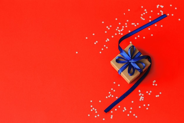 Вид сверху на рождественские подарки с лентой на фоне красной бумаги с серебряными звездами. Copyspace.