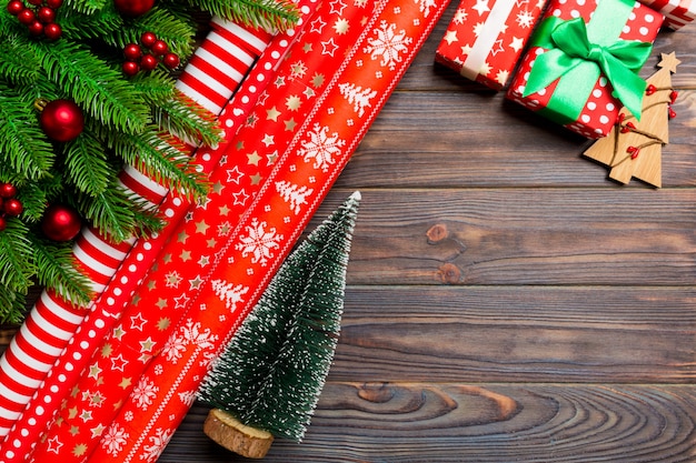 Top view of Christmas made of fir tree, rolled wrapping paper and other decorations on wooden.