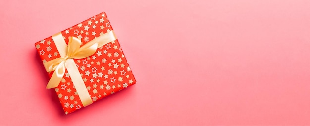 コピースペース付きの生きたサンゴの背景に金色の弓付きのクリスマスプレゼントボックスをトップビューで表示