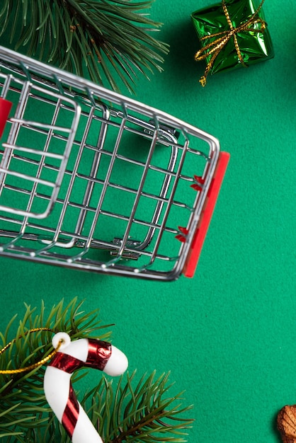 Top view of Christmas shopping design concept with gift box and shopping cart on green table background