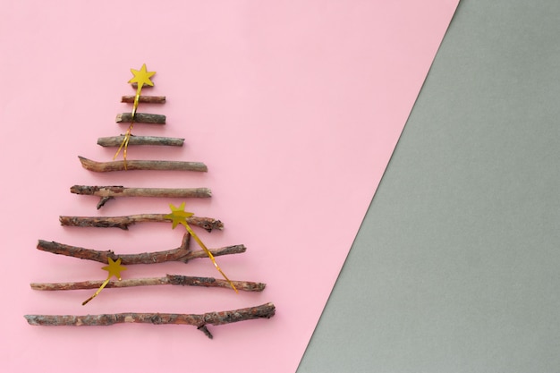 Top view christmas tree silhouette  made from wooden twigs and  on a pastel pink and gray background with copy space