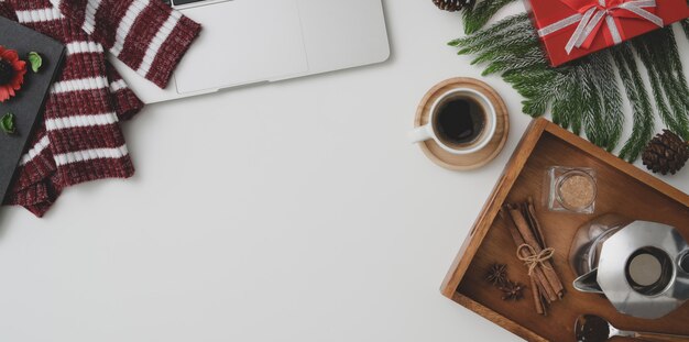 Top view of Christmas workspace with laptop computer, coffee cup and present on vintage wooden desk 