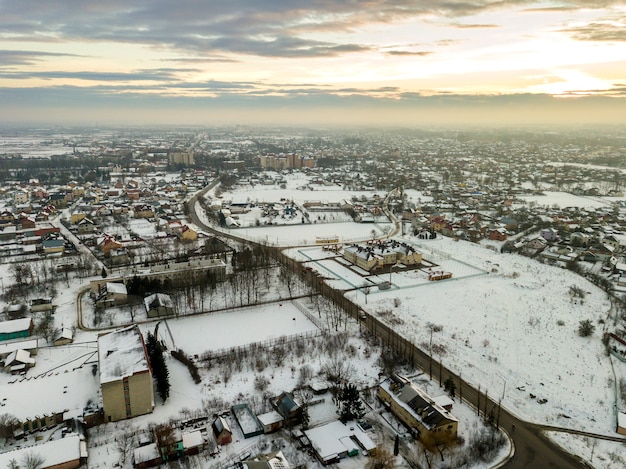 Top view of city suburbs or small town nice houses on winter morning on cloudy sky background. Aerial drone photography concept.