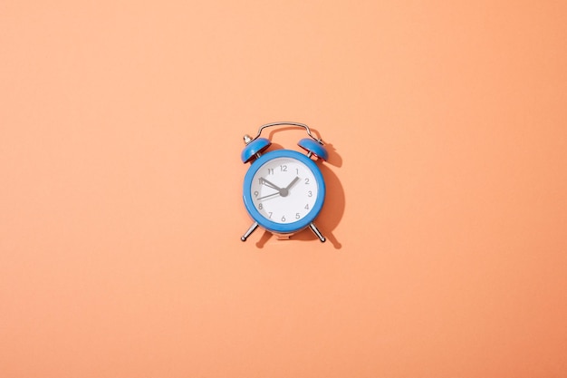 Top view of classic alarm clock on peach background