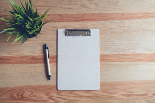 Top view clipboard with pen and white paper on the table background. mock up for text bann