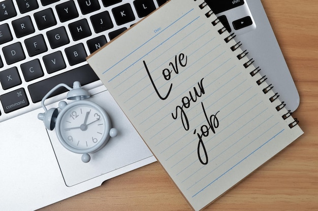 Photo top view of clock laptop and notebook written with love your job