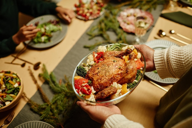 感謝祭のウィットを祝っている間、テーブルに食べ物を持って来るアフリカ系アメリカ人の女性の上面図のクローズアップ...