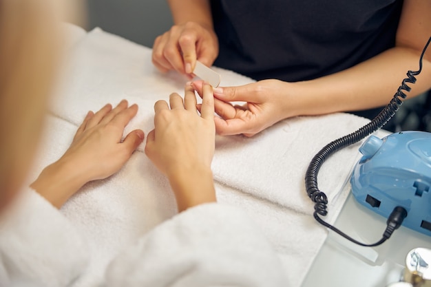 Top view close up of female hands being polished and designed with hand instrument in spa salon