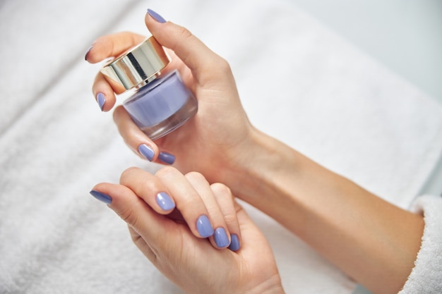 Top view close up of female hands with bright manicure holding gel polish above towel