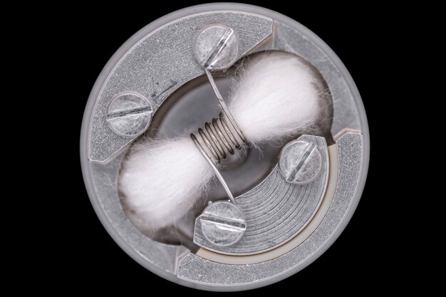 Top view, close up, macro shot of single space coil with japanese organic cotton wick in high end rebuildable dripping atomizer for flavour chaser isolated on black background, vaping device