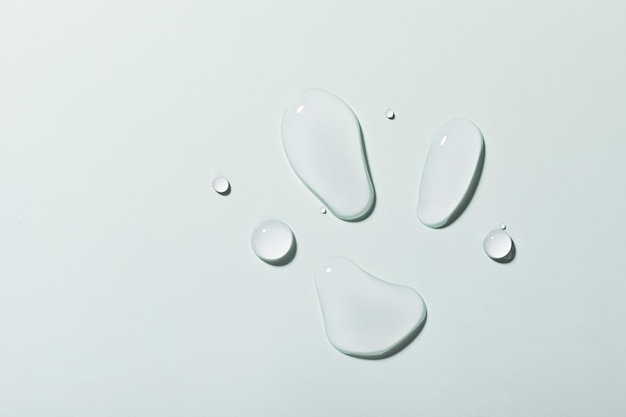 Top view closeup of multiple water drops on a light blue background