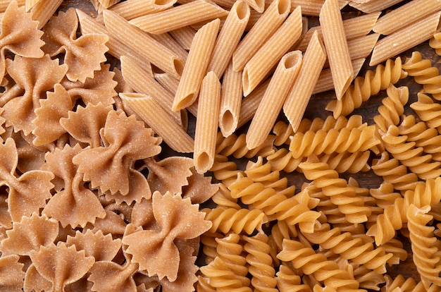 Top view, closeup of whole wheat farfalle, penne and fusilli pasta.