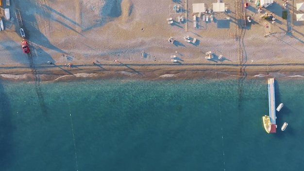 Foto vista dall'alto della costa mare e spiaggia sabbiosa giornata di sole molo in mare sedie a sdraio e ombrelloni sulla spiaggia