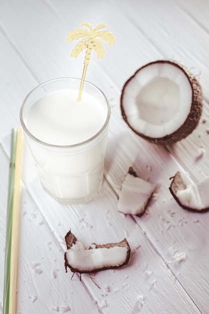 Top view of coconut milk in glass with coconut fruit on wooden table Alternative milk Tropical