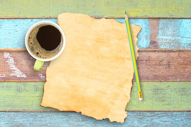 Top view coffee cuppencil and old paper on office wooden table