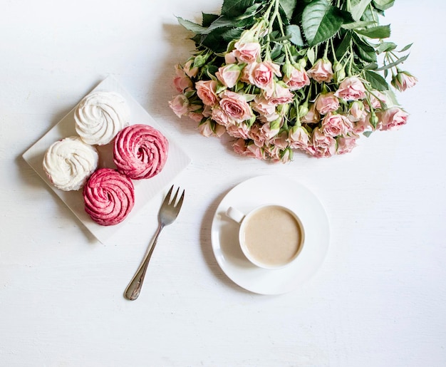 Top view of coffee marshmallows and roses on white background