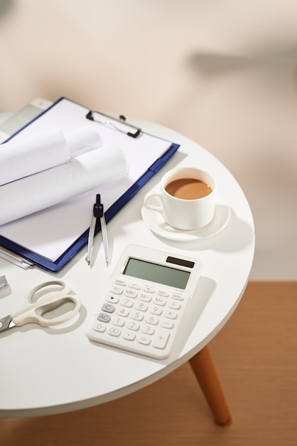 Top view of coffee notebook empty page, calculator, scissors on white table