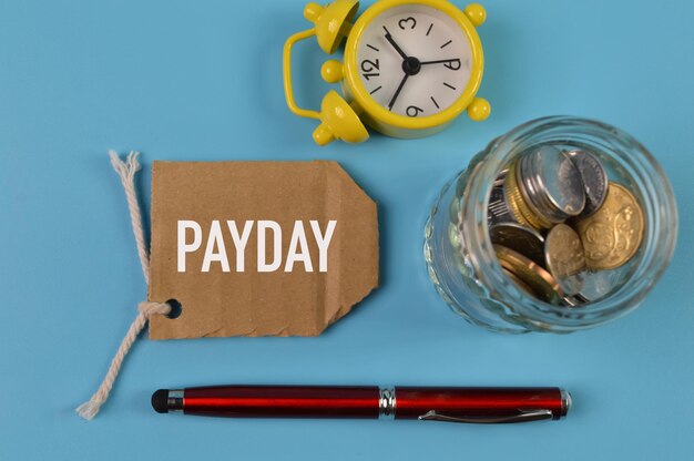 Photo top view of coins pen clock and label tag written with payday