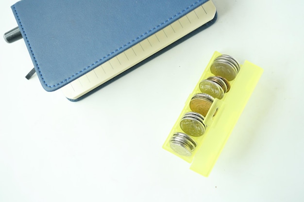 Top view of coins in a plastic box on white background