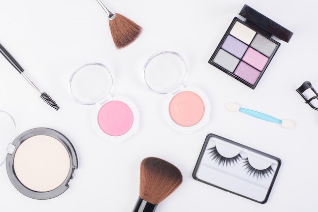 Top view of A collection of cosmetic beauty products arranged around a blank space on a white background.