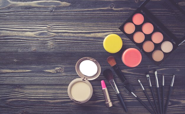 Top view a collection of cosmetic makeup on wooden table background.