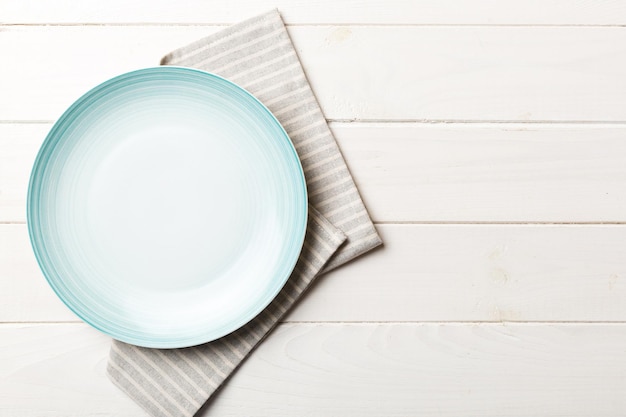 Top view on colored background empty round blue plate on tablecloth for food Empty dish on napkin with space for your design