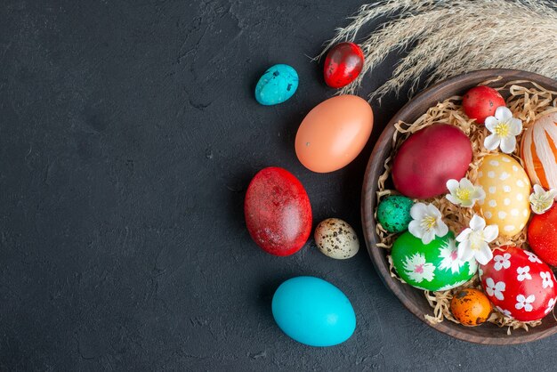 茶色のプレートの暗い背景の休日のカラフルな華やかな水平春novruz内の上面図色のデザインされた卵