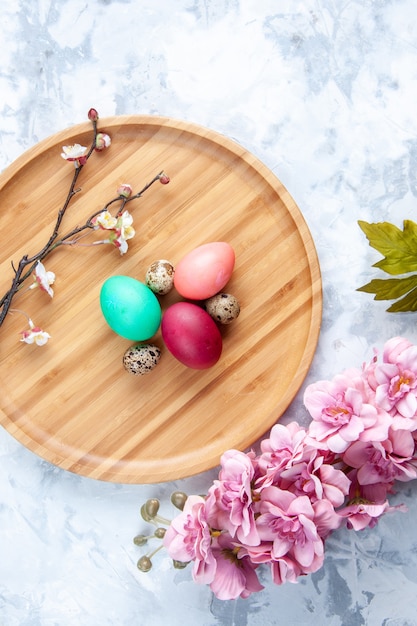 top view colored easter eggs on cutting board on white surface