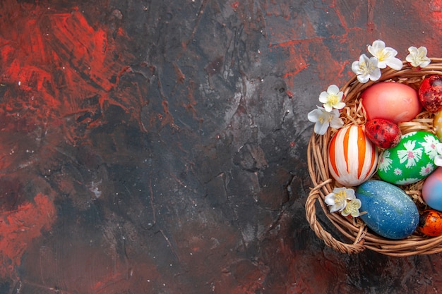 top view colored easter eggs inside basket on dark surface