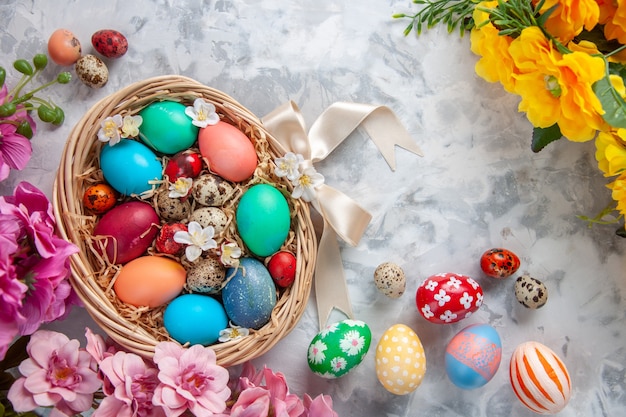 흰색 표면에 바구니 안에 있는 상위 뷰 컬러 부활절 달걀 봄 화려한 꽃 휴일 화려한 개념 부활절