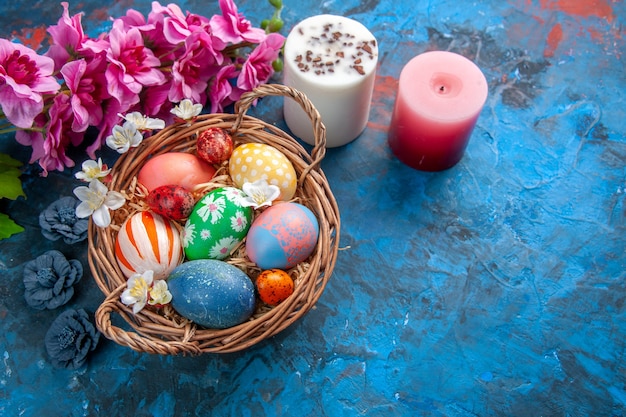 Фото Вид сверху цветные пасхальные яйца внутри корзины с цветами на синей поверхности