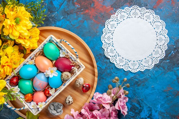 Photo top view colored easter eggs inside box on cutting board blue surface