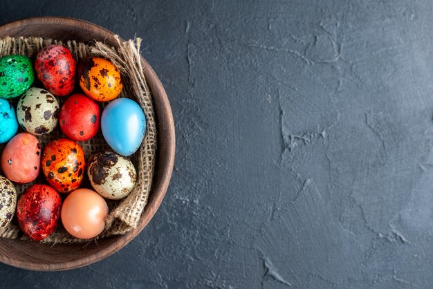 top view colored easter eggs inside brown plate dark surface