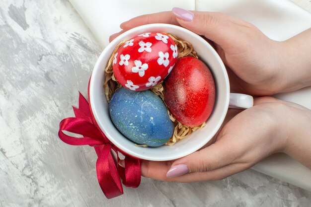 top view colored easter eggs inside cup on white surface