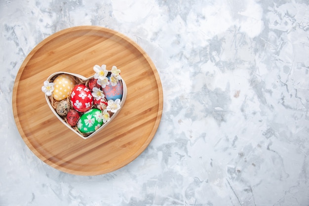 top view colored easter eggs inside heart shaped box on cutting board white surface concept colourful holiday paint ornate spring free space