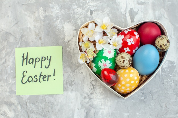 top view colored easter eggs inside heart shaped box on white surface