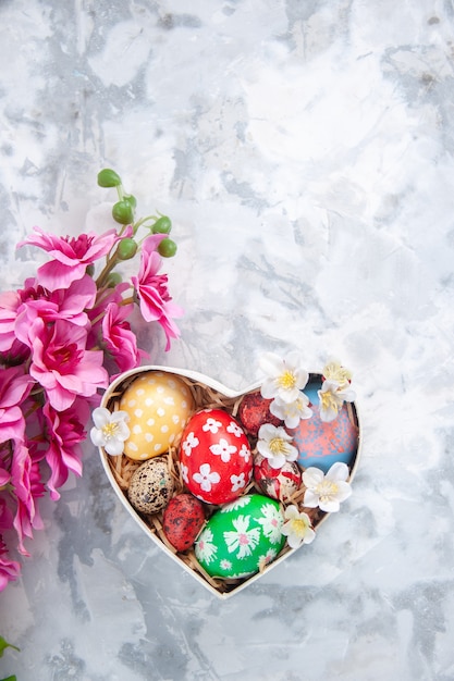 top view colored easter eggs inside heart shaped box with flowers white surface concept colourful ornate spring