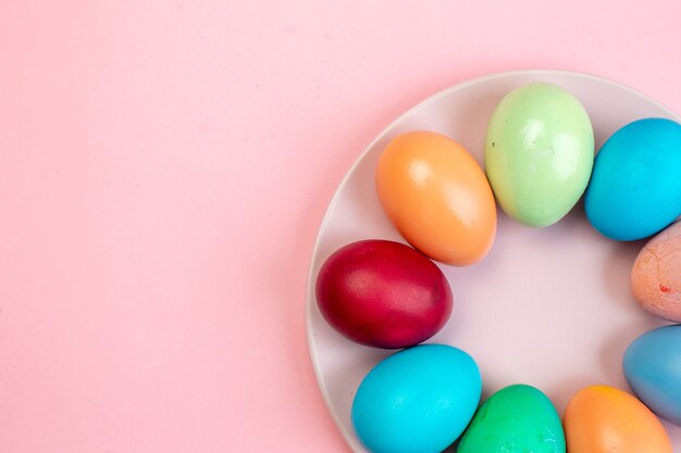 top view colored easter eggs inside plate on pink surface