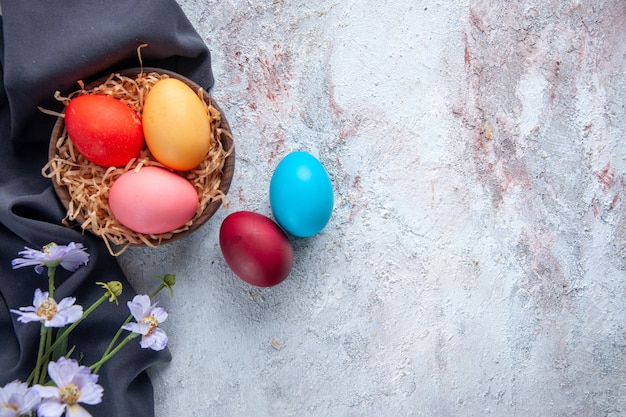 top view colored easter eggs inside plate with straw on white surface