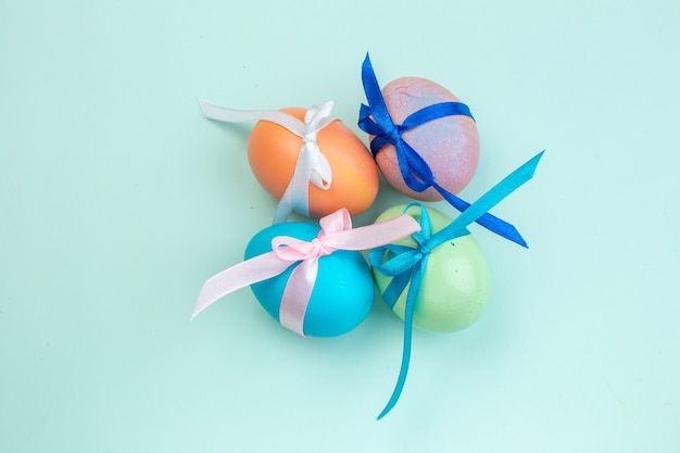 top view colored easter eggs tied with cute bows on blue surface