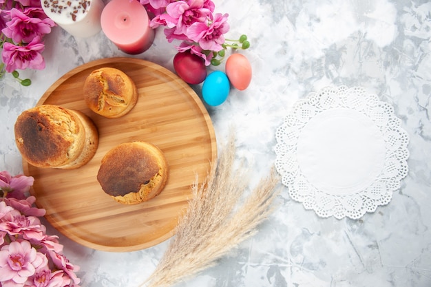 top view colored easter eggs with flowers and cakes on white surface