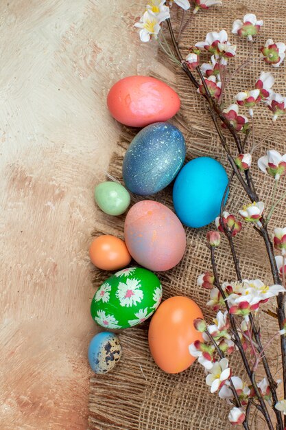 Vista dall'alto uova di pasqua colorate con fiori bianchi su superficie chiara