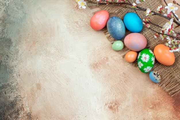 top view colored easter eggs with white flowers on light surface